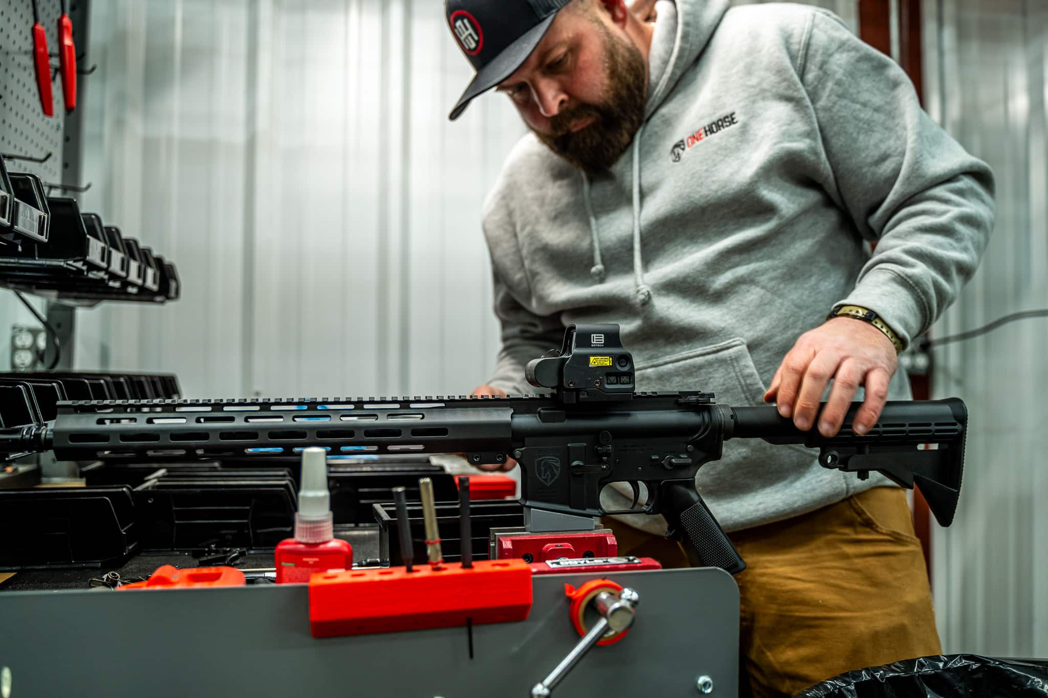 A One Horse technician assembling an AR-15 rifle at a workbench in the shop