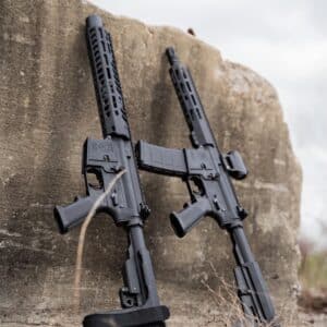 Two American-made rifles with sleek black finishes, showcasing precision design and craftsmanship against a rugged backdrop.