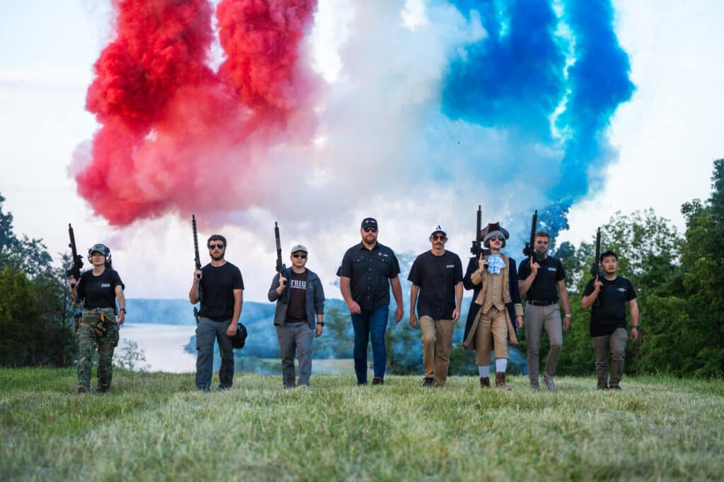Group of firearm enthusiasts confidently holding rifles, with colorful smoke in the background, showcasing American-made craftsmanship.