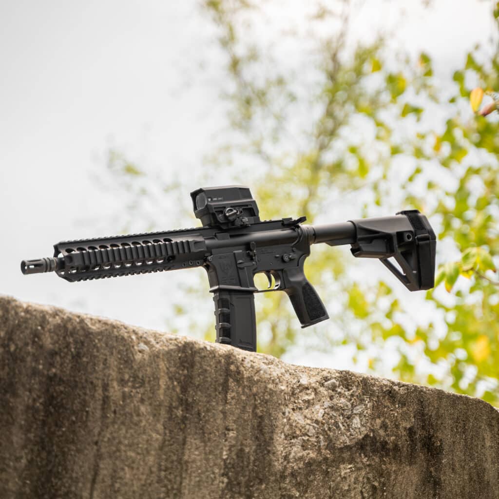 A One Horse 10.5-inch Express QUAD pistol with a stabilizing brace and an optic, resting on a concrete ledge.