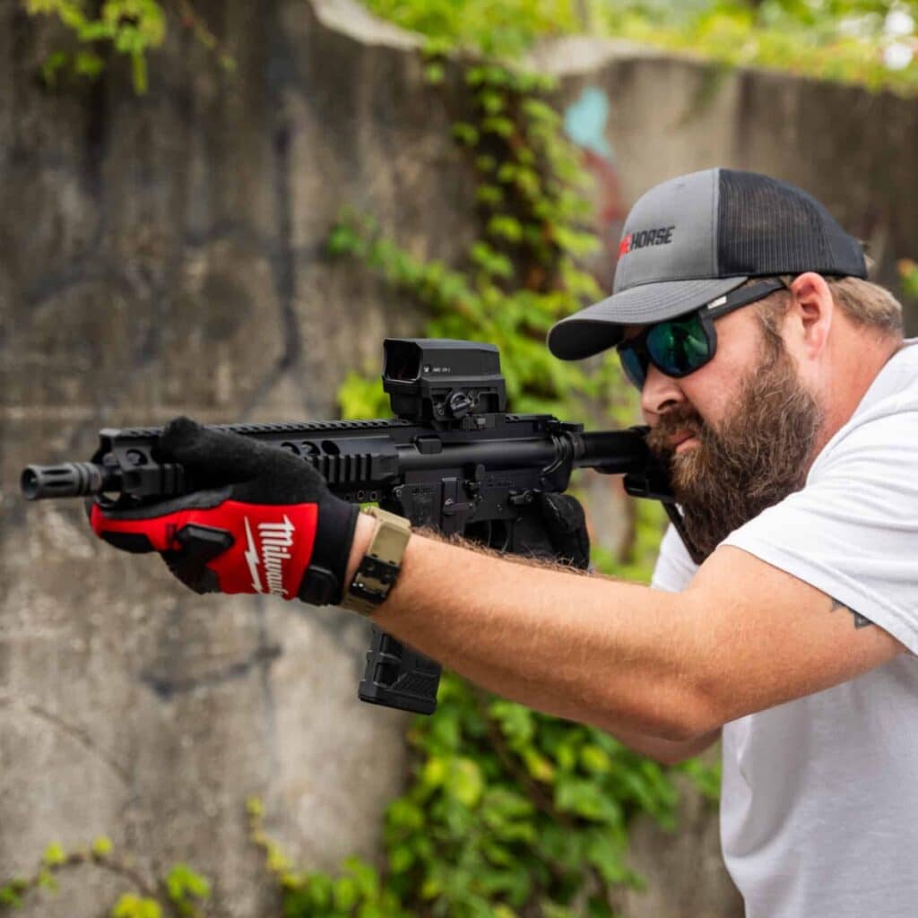 Shooter aiming a One Horse AR-15 rifle with a red dot sight