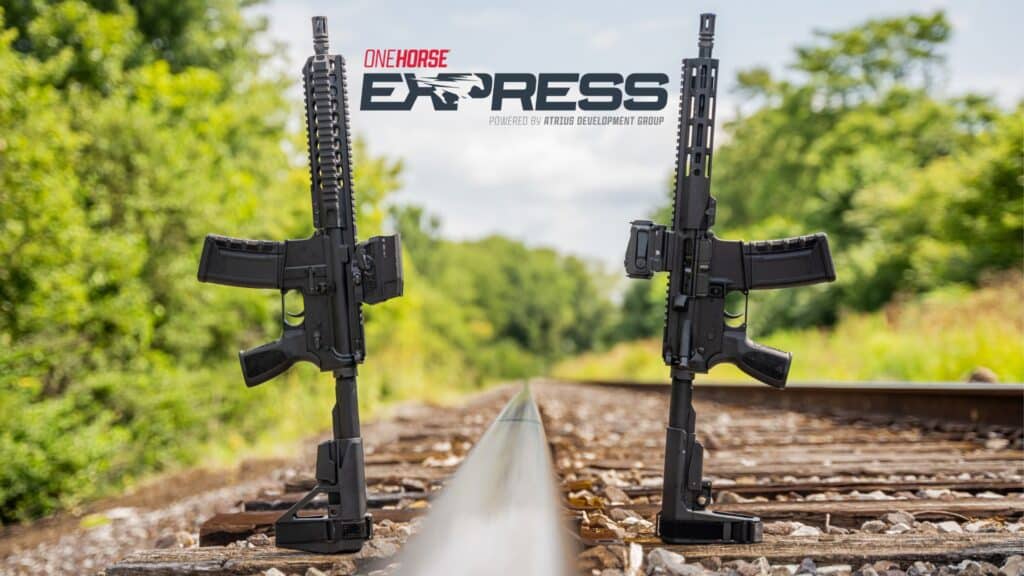 Two black American-made rifles with tactical accessories stand upright on railroad tracks, featuring the One Horse Express logo in the background.