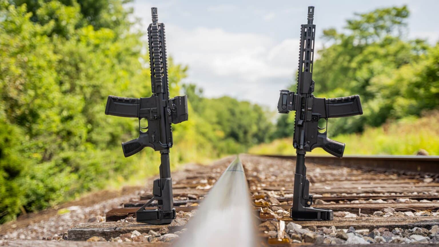 Two One Horse Express 10.5-inch pistols standing on railroad tracks, the Quad Rail on the left and the MLOK on the right